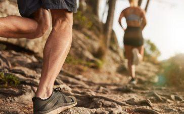 Pair running over rocky terrain in mountainous area.