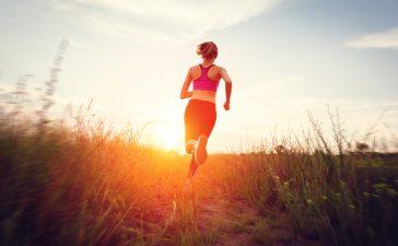 Women running into the sun enjoying her trail run